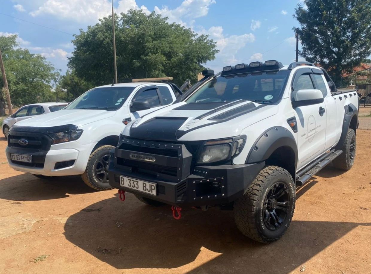 Two white Ford Ranger bakkies parked side by side