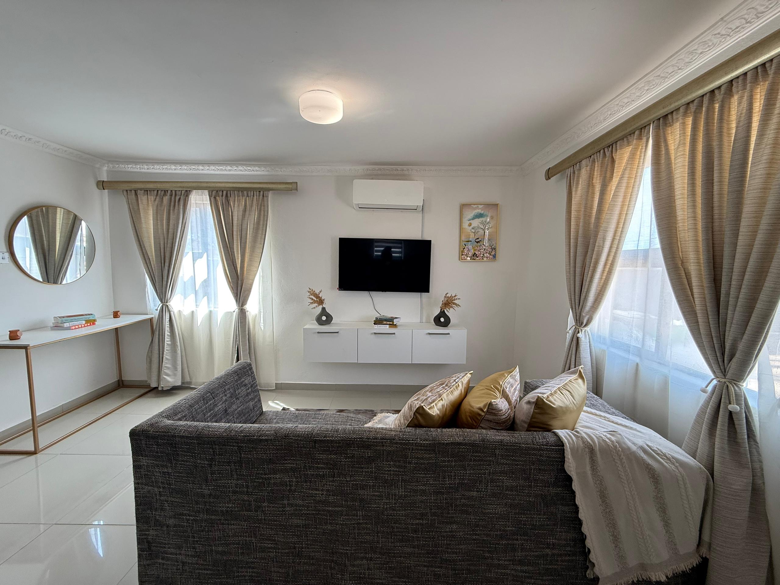 Living room with sofa, TV unit and curtains